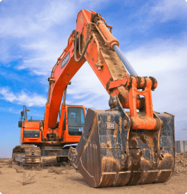 An orange excavation machine covered in dirt, resting beneath a blue cloudy sky.